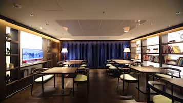 A hotel room with a TV, bookshelves, and a blue curtain.