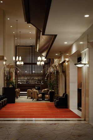 A hotel lobby with a red carpet, seating area, and a bar in the background. - ANA Crowne Plaza Fukuoka by IHG (Fukuoka)