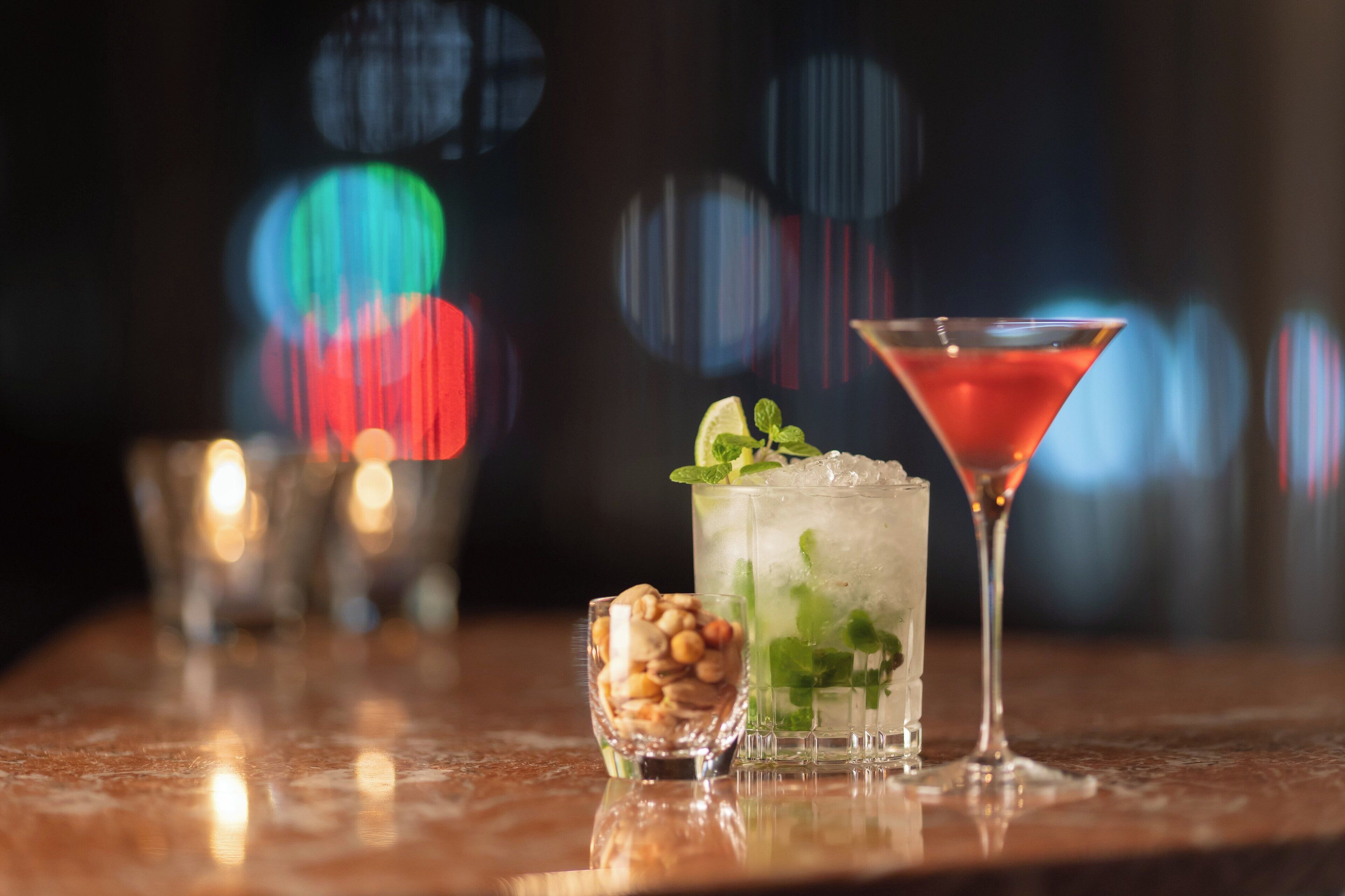 Eine Bar mit einem Martini-Glas, einem Mojito und einer kleinen Schale Nüsse.