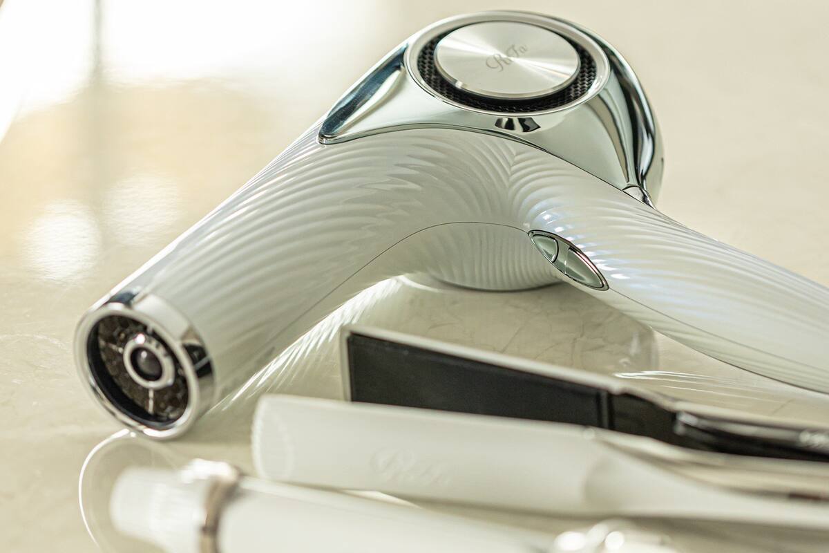 A modern, metallic hair dryer with a sleek design, placed on a reflective surface.