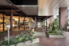 A covered outdoor area with a dining section, potted plants, and a pathway leading to a building entrance. - ANA Crowne Plaza Fukuoka by IHG (Fukuoka)
