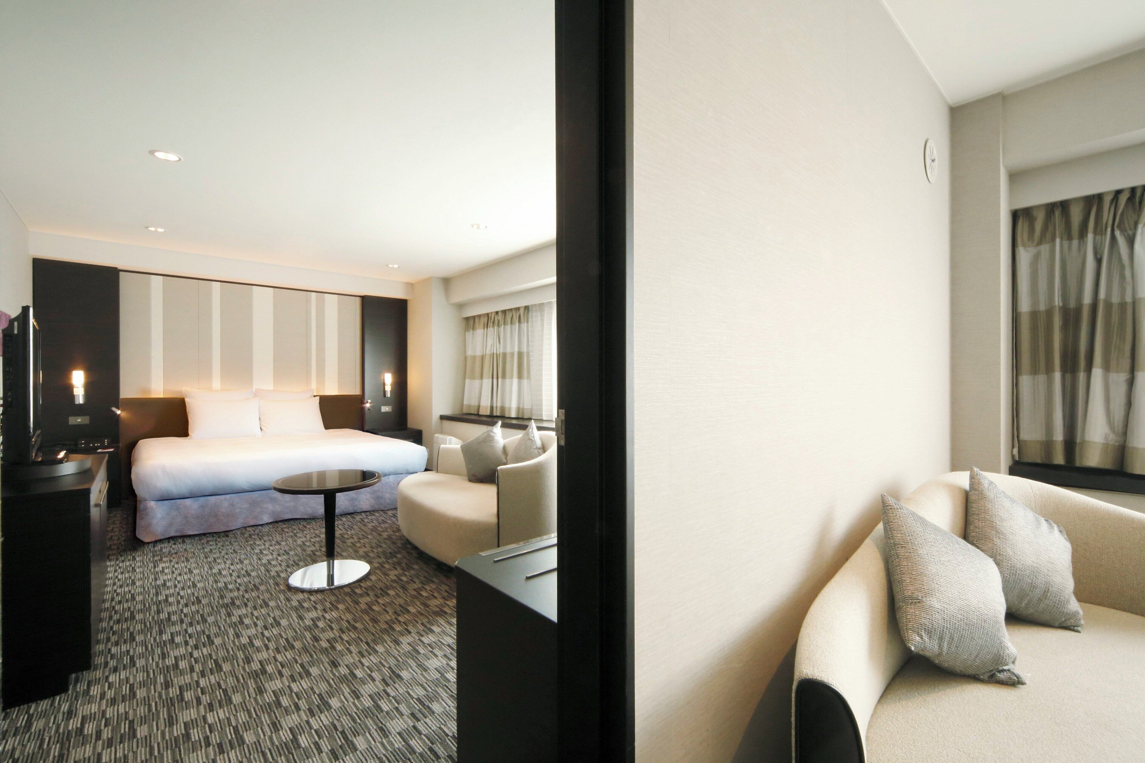 Ein Hotelzimmer mit einem Bett, einer Couch, einem kleinen Tisch und einem Fernseher.