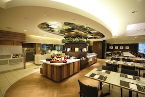 A modern restaurant with a central counter, dining tables, and a kitchen area. - ANA Crowne Plaza Fukuoka by IHG (Fukuoka)