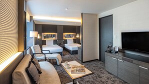 Quarto de hotel moderno com sofá, duas camas de solteiro, televisão e minibar.
