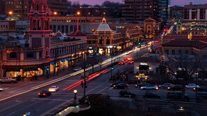 A cityscape with illuminated buildings and a busy street at dusk.