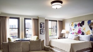 A hotel room with a large bed, a sofa, and a view of the city through large windows. - The Raphael Hotel, Autograph Collection (Kansas City)