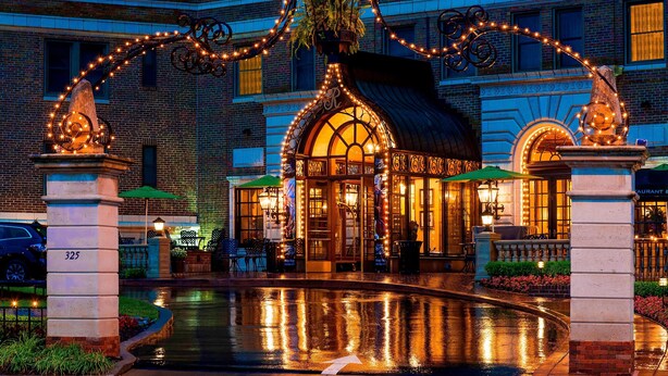 A hotel entrance with a brick facade, a fountain, and decorative lights. - The Raphael Hotel, Autograph Collection (Kansas City)
