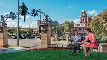 Guests can dine al fresco under a stone archway surrounded by a well-manicured lawn and urban views.