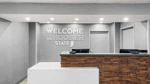 A reception area with a modern design, featuring a reception desk with a wooden panel back and a grey wall with a welcome sign.