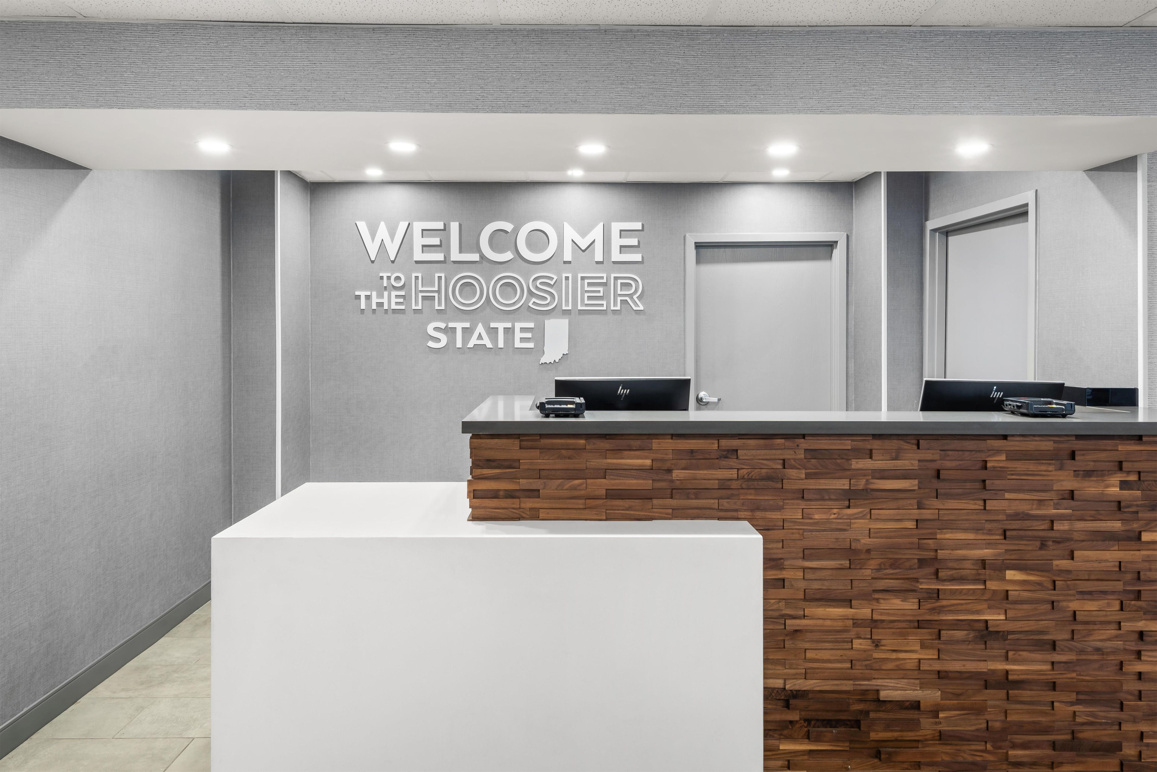 En reception med et skilt der står 'WELCOME THE HOOSIER STATE', en trævæg og et moderne design.