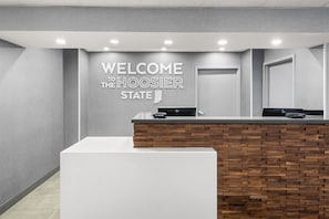 Un comptoir d’accueil avec une pancarte indiquant « BIENVENUE DANS L’ÉTAT DE L’INDIANA », un mur décoratif en bois et un design moderne.
