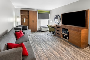 Une chambre d’hôtel équipée d’un canapé, d’un bureau, d’une télévision et d’une armoire.