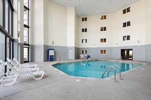 Une piscine intérieure avec des chaises longues, un vestiaire et un petit coin salon.