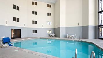 Una piscina interior con vistas despejadas del área de la piscina, incluyendo el borde de la piscina, una silla de salvavidas y un conjunto de escaleras que bajan a la piscina.