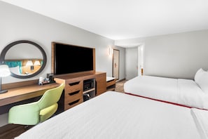 Une chambre d’hôtel comprenant un lit, un bureau avec une chaise, une télévision, un four à micro-ondes et un miroir.
