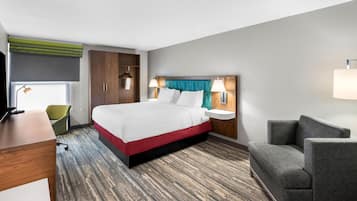 Una habitación de hotel con cama, mesitas de noche, escritorio, silla y armario.
