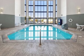An indoor swimming pool with clear glass walls, a tiled floor, and a view of the outside.