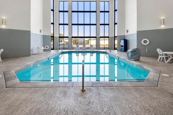 Una piscina interior con paredes de vidrio transparente, suelo de baldosas y un flotador en la pared.