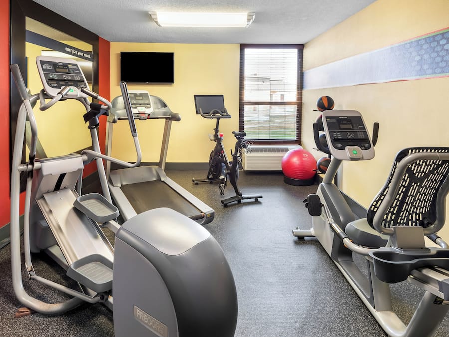 Un gimnasio con cintas de correr, bicicletas estáticas y pelotas de ejercicio.