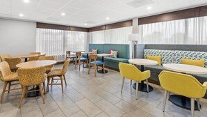 A modern dining area with round tables and chairs, a sofa, and a lamp.
