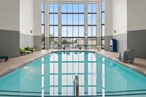 An indoor swimming pool with clear glass walls, a tiled floor, and several lounge chairs. - Hampton Inn Indianapolis-N.E./Castleton (Indianapolis)