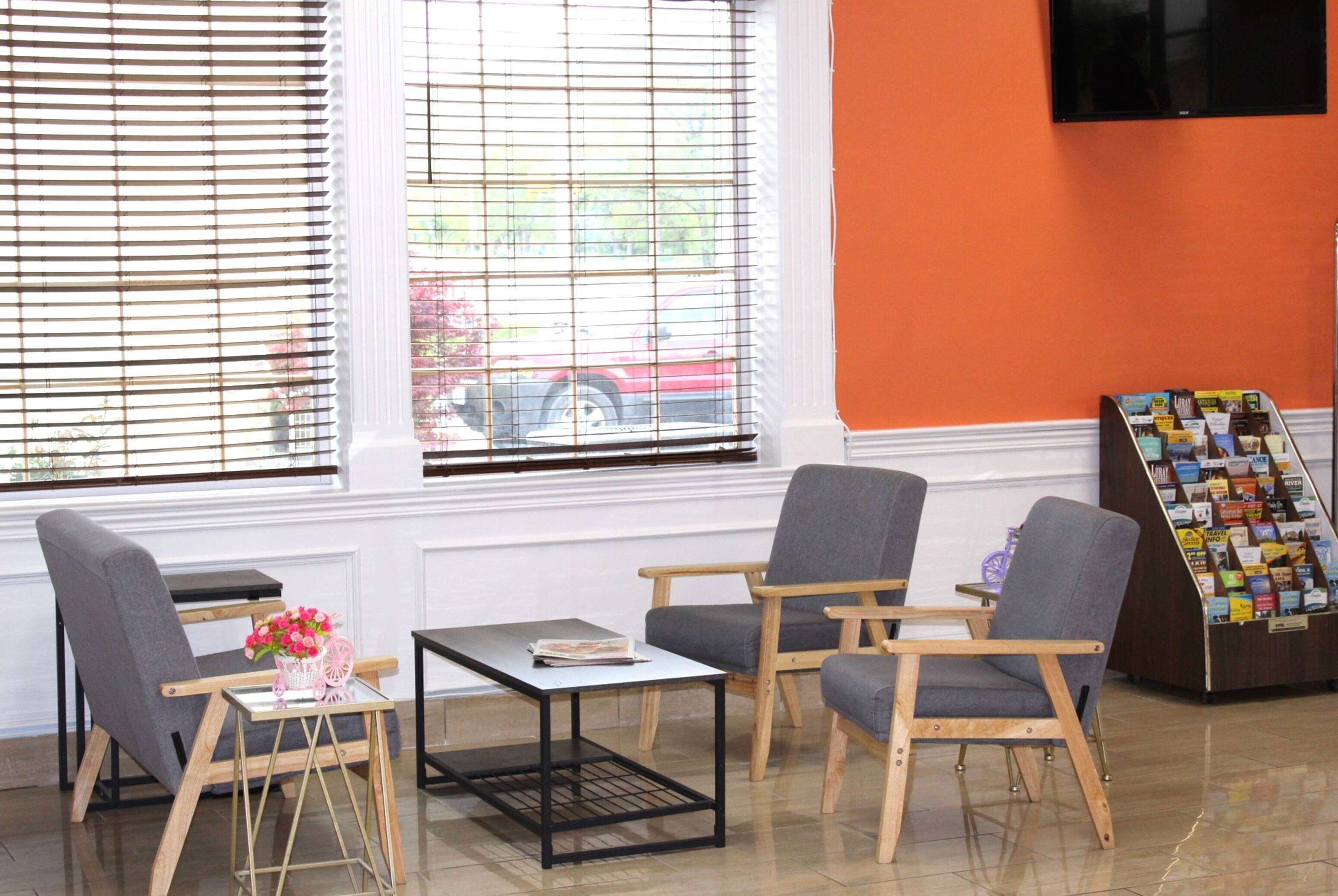 A room with a window, a magazine rack, and two chairs.