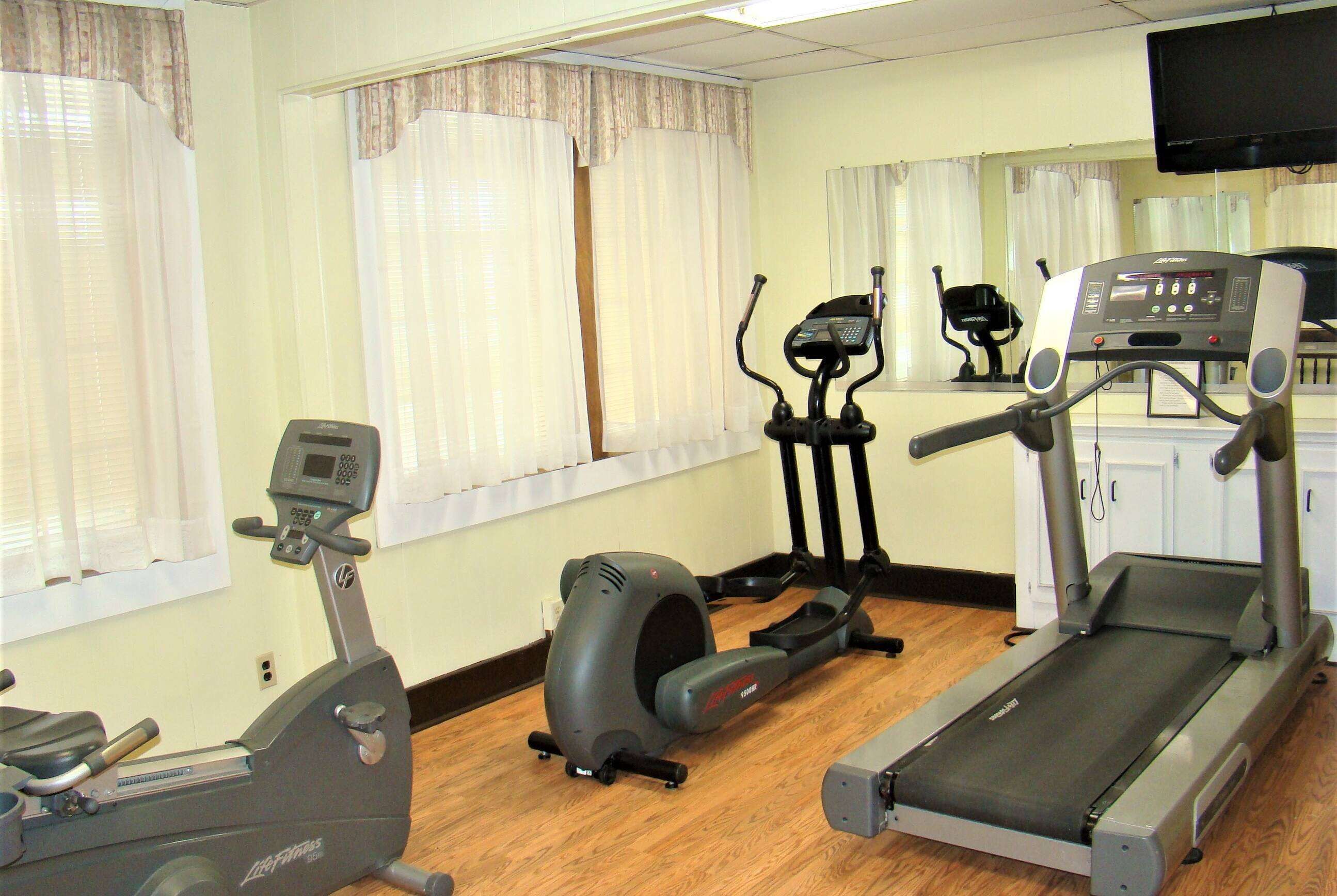 Un gimnasio con una elíptica, una bicicleta estática y una cinta de correr.
