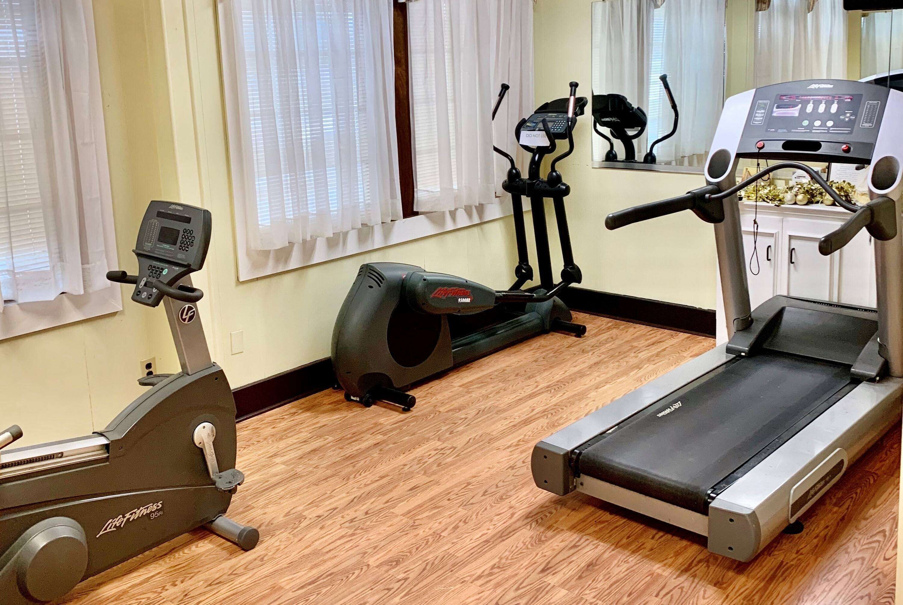 A home gym with a treadmill, elliptical, and stationary bike.