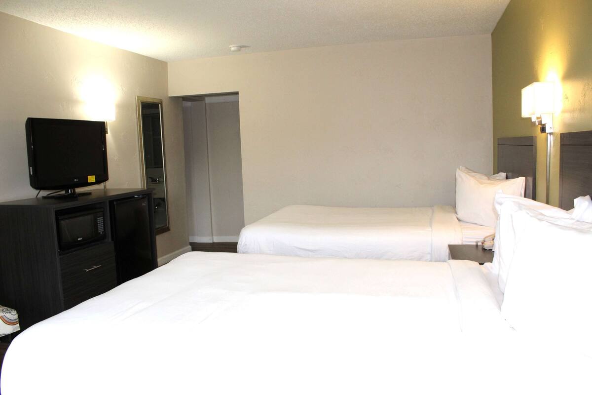 A hotel room with two beds, a TV, a microwave, and a closet.