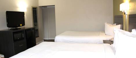 A hotel room with two beds, a TV, a microwave, and a closet.