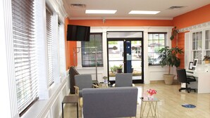 A room with two grey armchairs, a small table with a vase of flowers, a television mounted on the wall, and a desk with a computer. - Baymont by Wyndham Front Royal Near Shenandoah National Park (Front Royal)