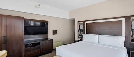 Habitación de hotel con una cama grande, televisión, armario y una pequeña zona de estar.