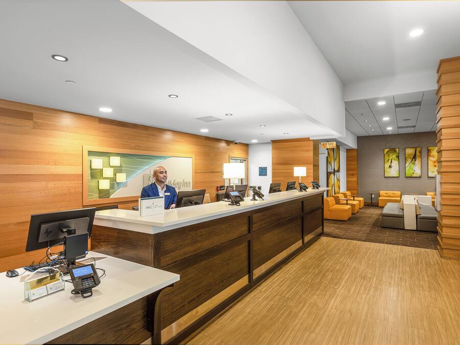 A hotel reception area with a wooden reception desk, computers, and seating area with sofas.