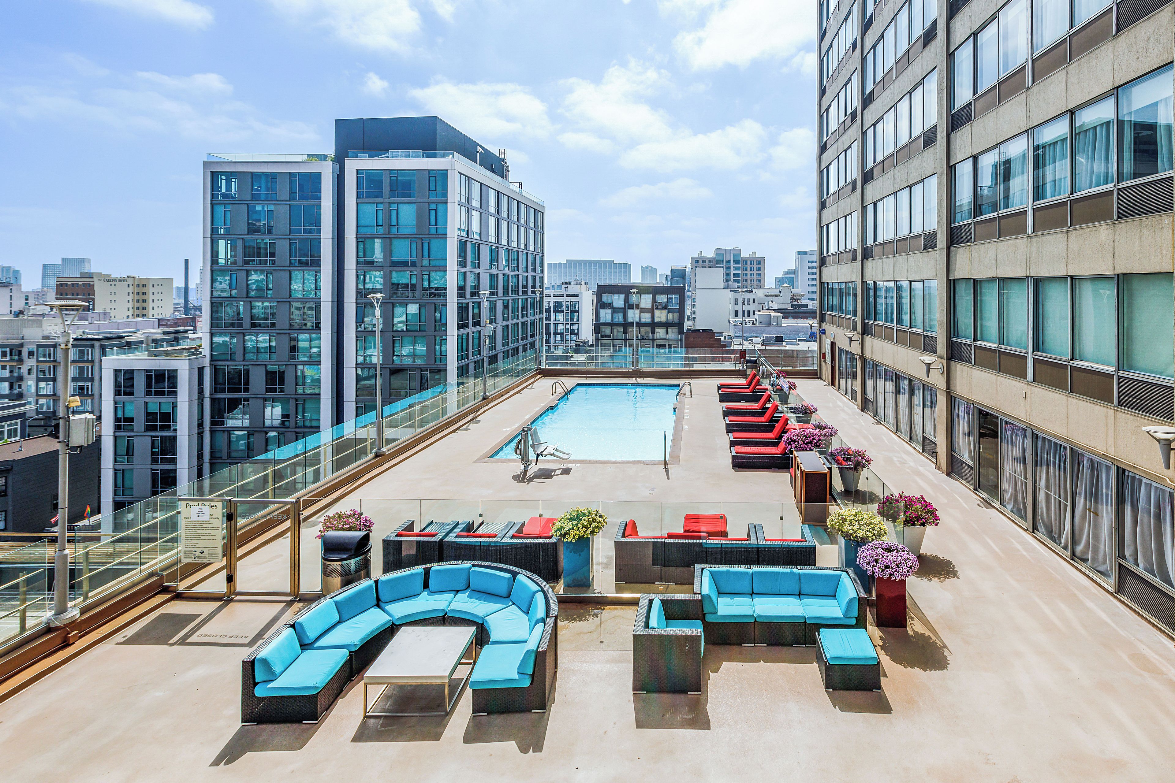 A rooftop pool area with modern outdoor furniture and a cityscape view.