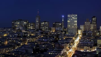 A nighttime cityscape with a dense cluster of buildings, including high-rise structures and a variety of architectural styles.