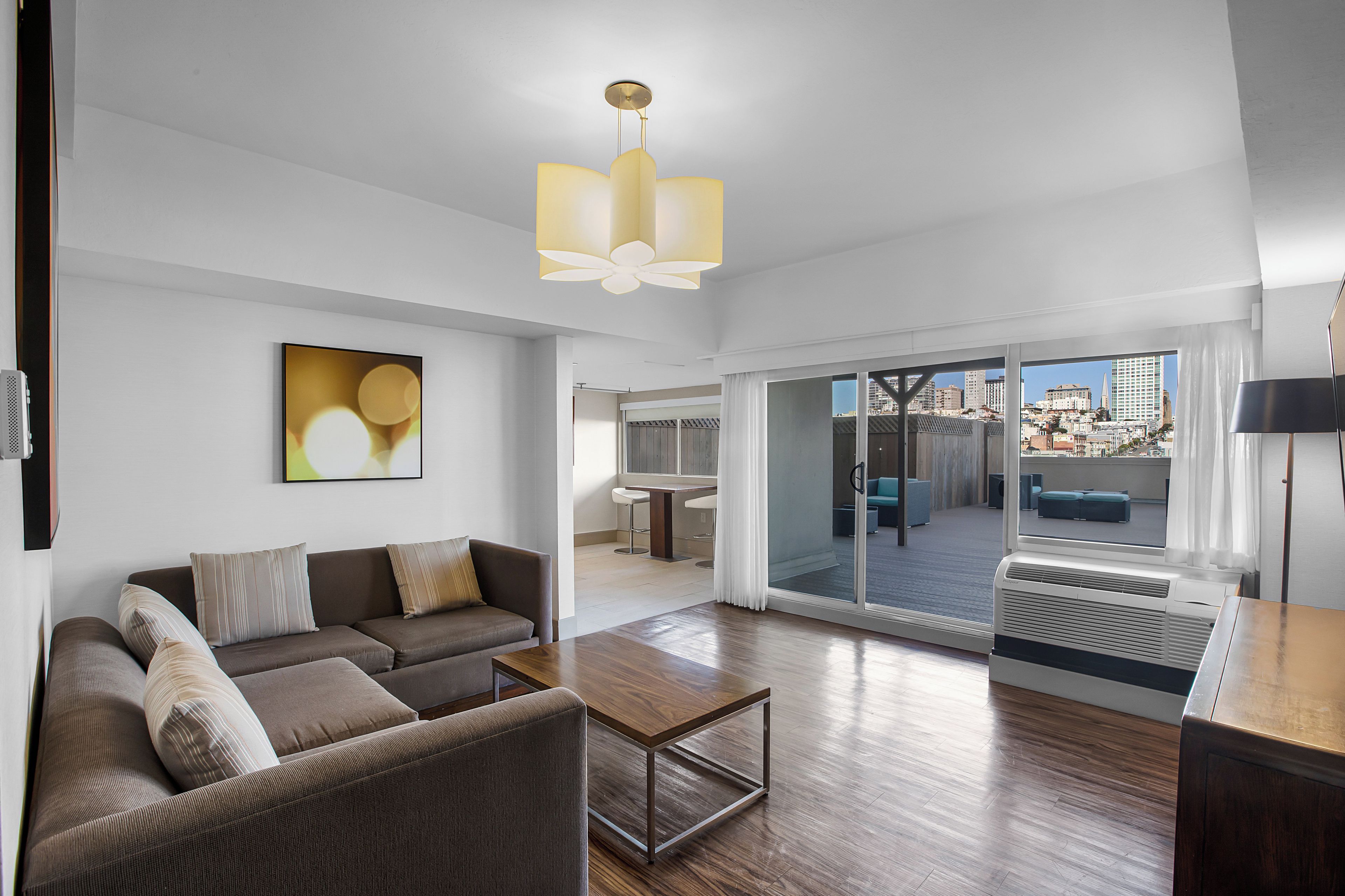 A modern living room with a sofa, a coffee table, and a large window offering a city view.