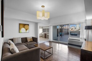 A modern living room with a sofa, a coffee table, and a large window offering a city view. - Holiday Inn Golden Gateway by IHG (San Francisco)