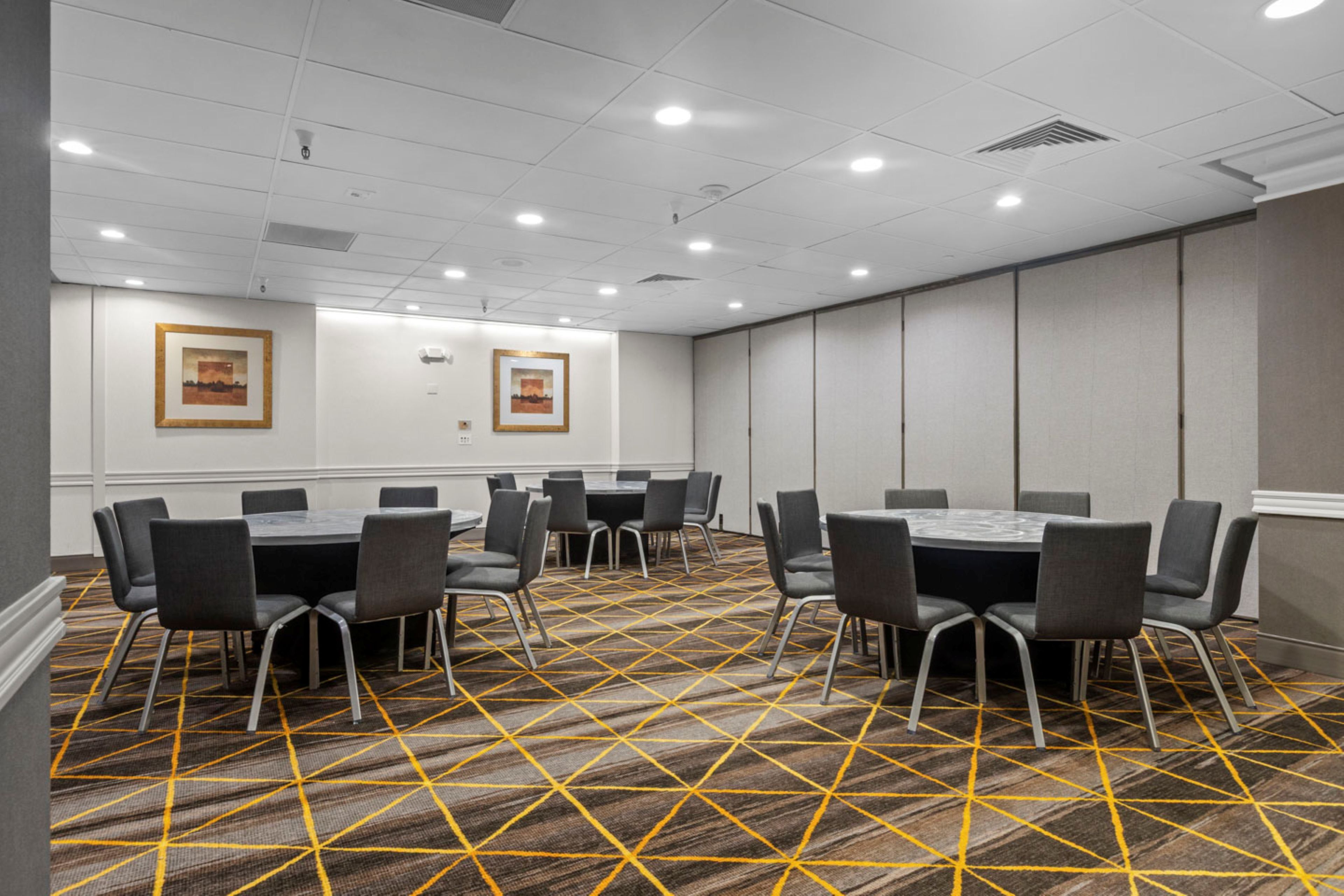A conference room with a patterned carpet, multiple tables, and chairs.