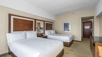 Hotelkamer met twee bedden, een houten hoofdeinde, een spiegel, een nachtkastje, een dressoir en een vloerbedekking.