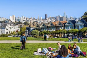 A park with people relaxing on the grass, a city skyline in the background, and Victorian-style houses. - Holiday Inn Golden Gateway by IHG (San Francisco)