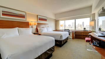 A hotel room with two beds, a desk, a chair, and a large window with a city view.