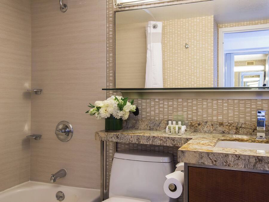 A bathroom with a shower, toilet, sink, and mirror.