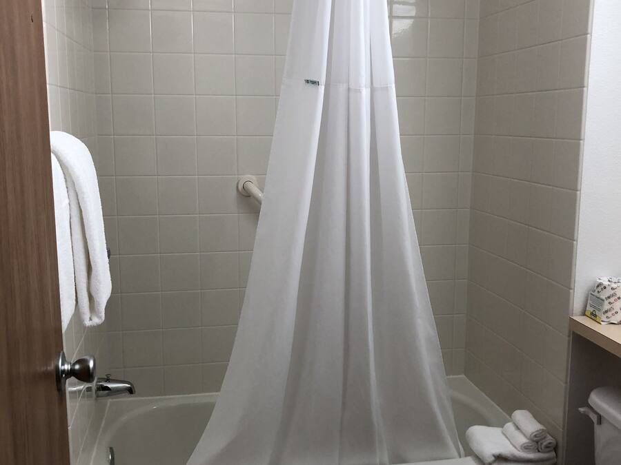 A bathroom with a bathtub, toilet, and a shower curtain.