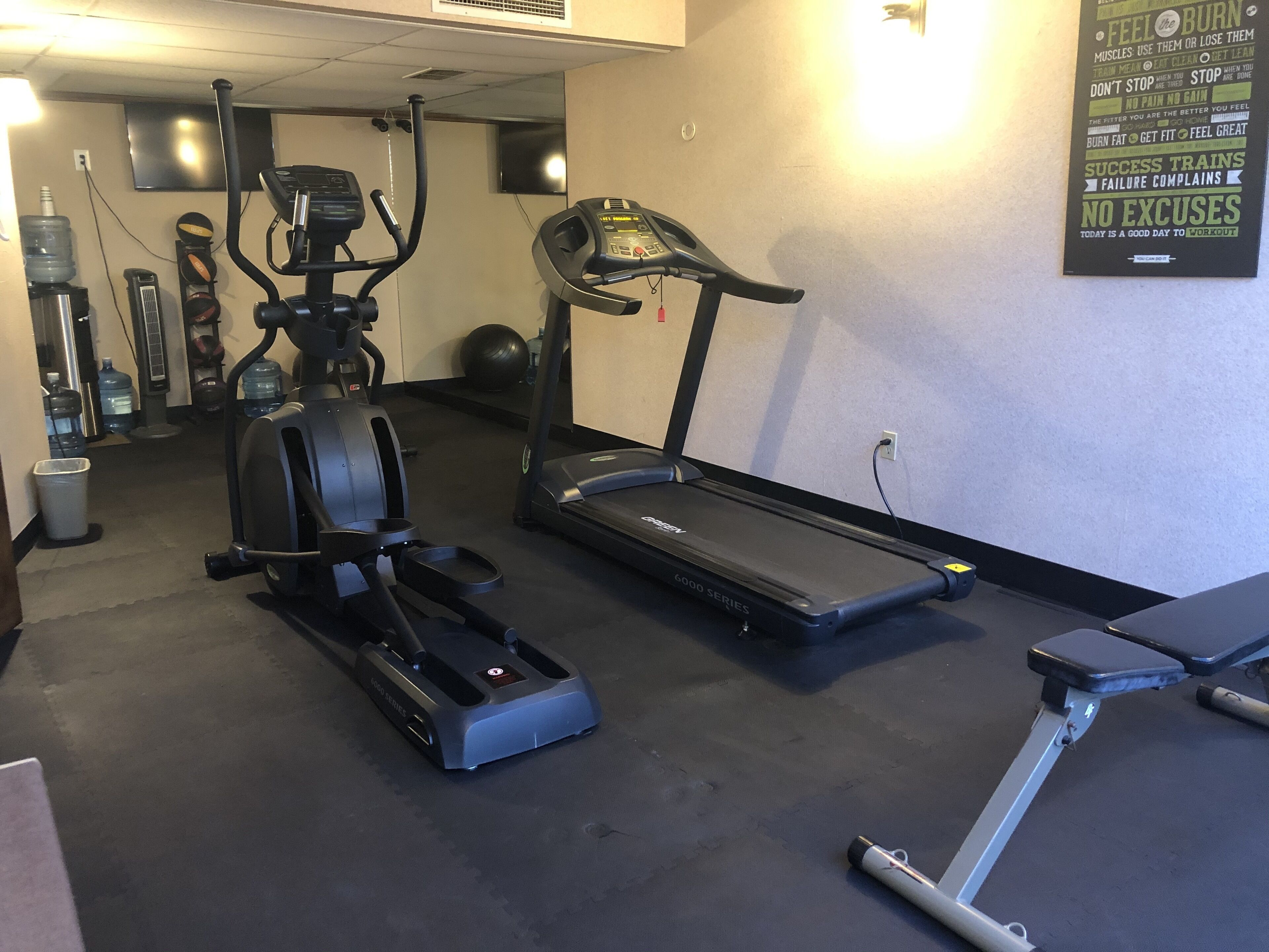 A gym with cardio equipment including a treadmill, elliptical, and stationary bike.