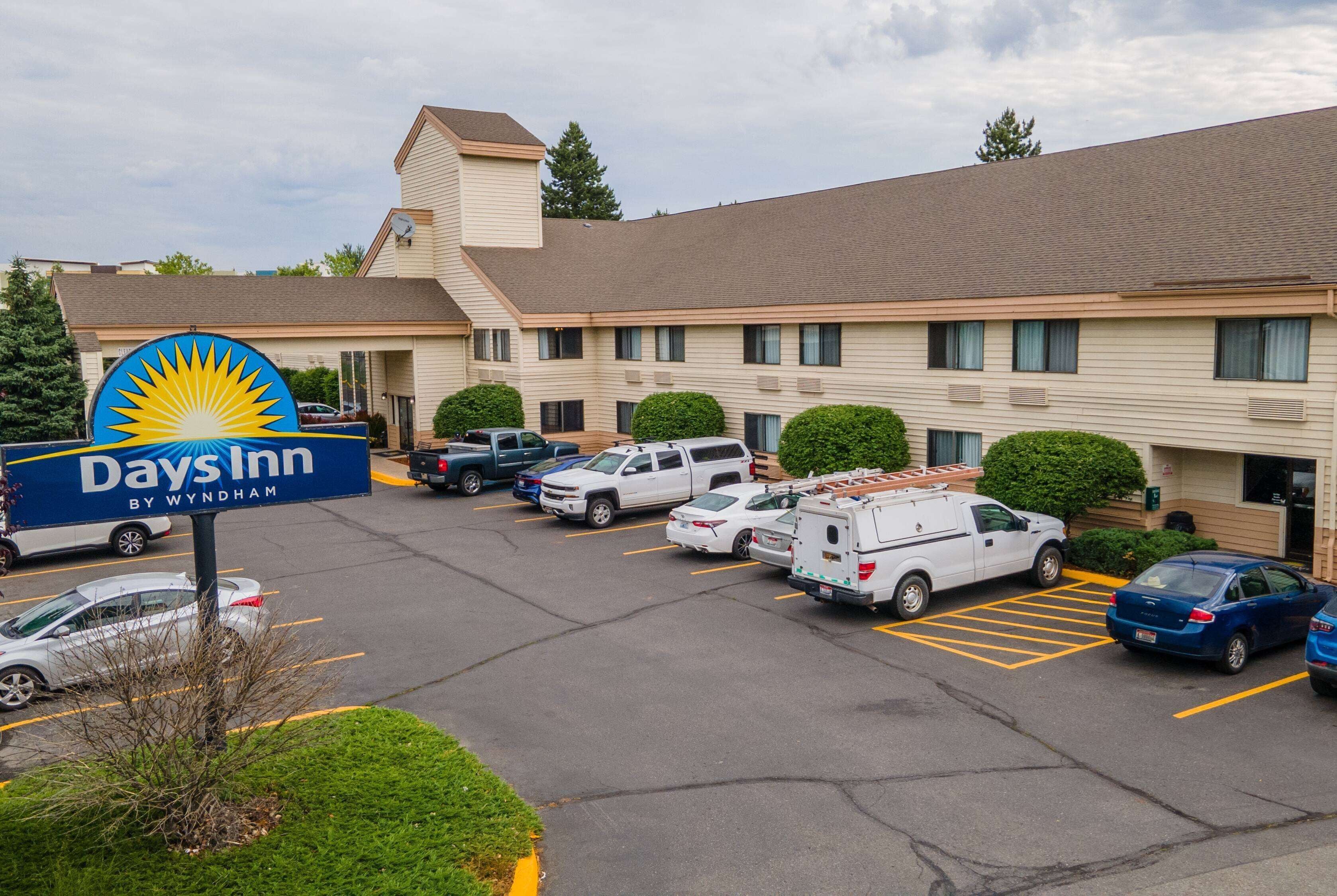A Days Inn by Wyndham with a parking lot containing several vehicles, including a white van and a blue car.