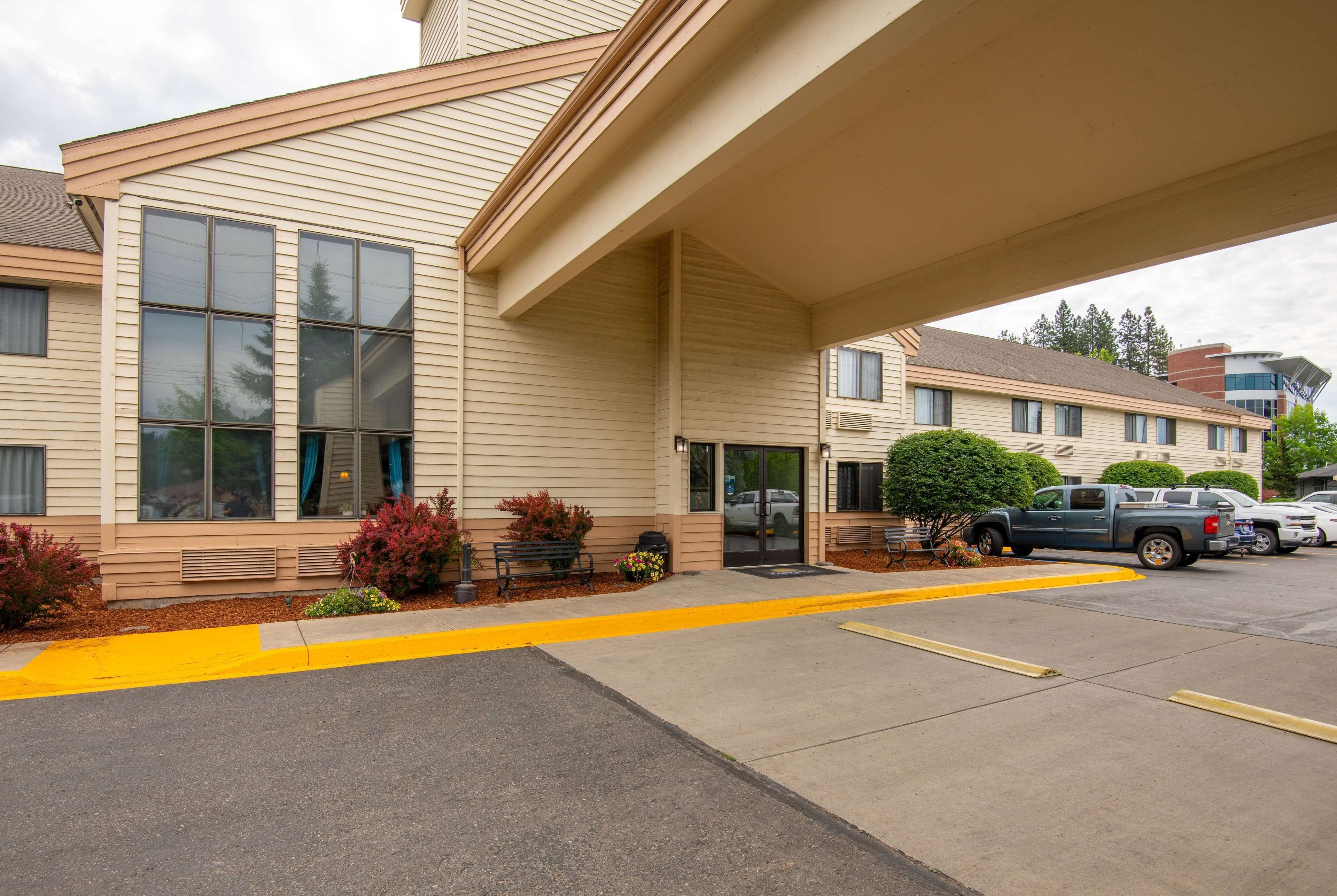 A hotel with a covered entrance, large windows, and a parking area with yellow lines.