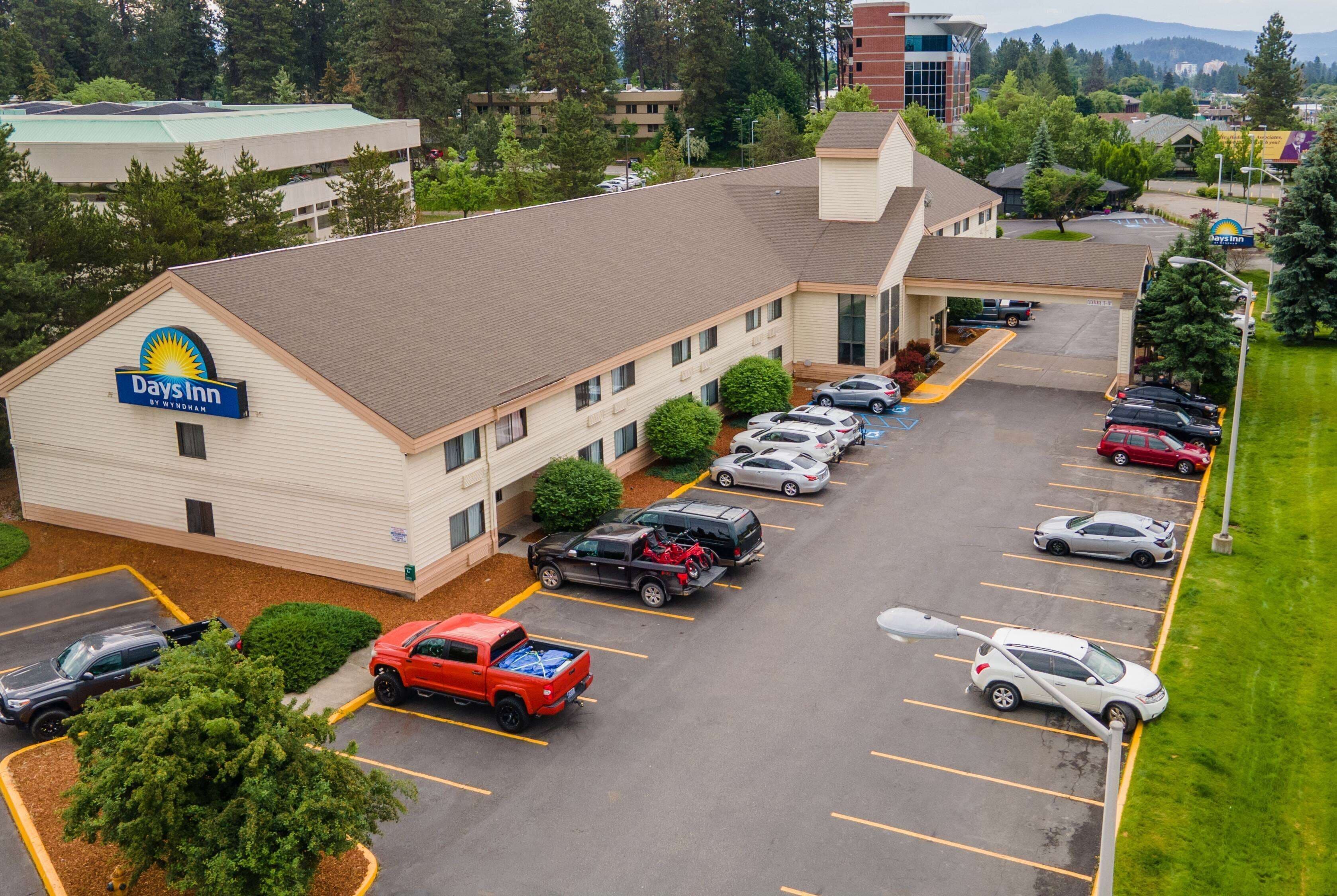 Un hotel Days Inn con un estacionamiento que contiene varios coches y una camioneta roja.