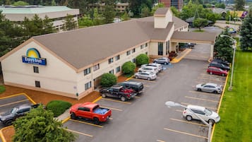 Un hotel Days Inn con un estacionamiento que contiene varios coches y una camioneta roja.