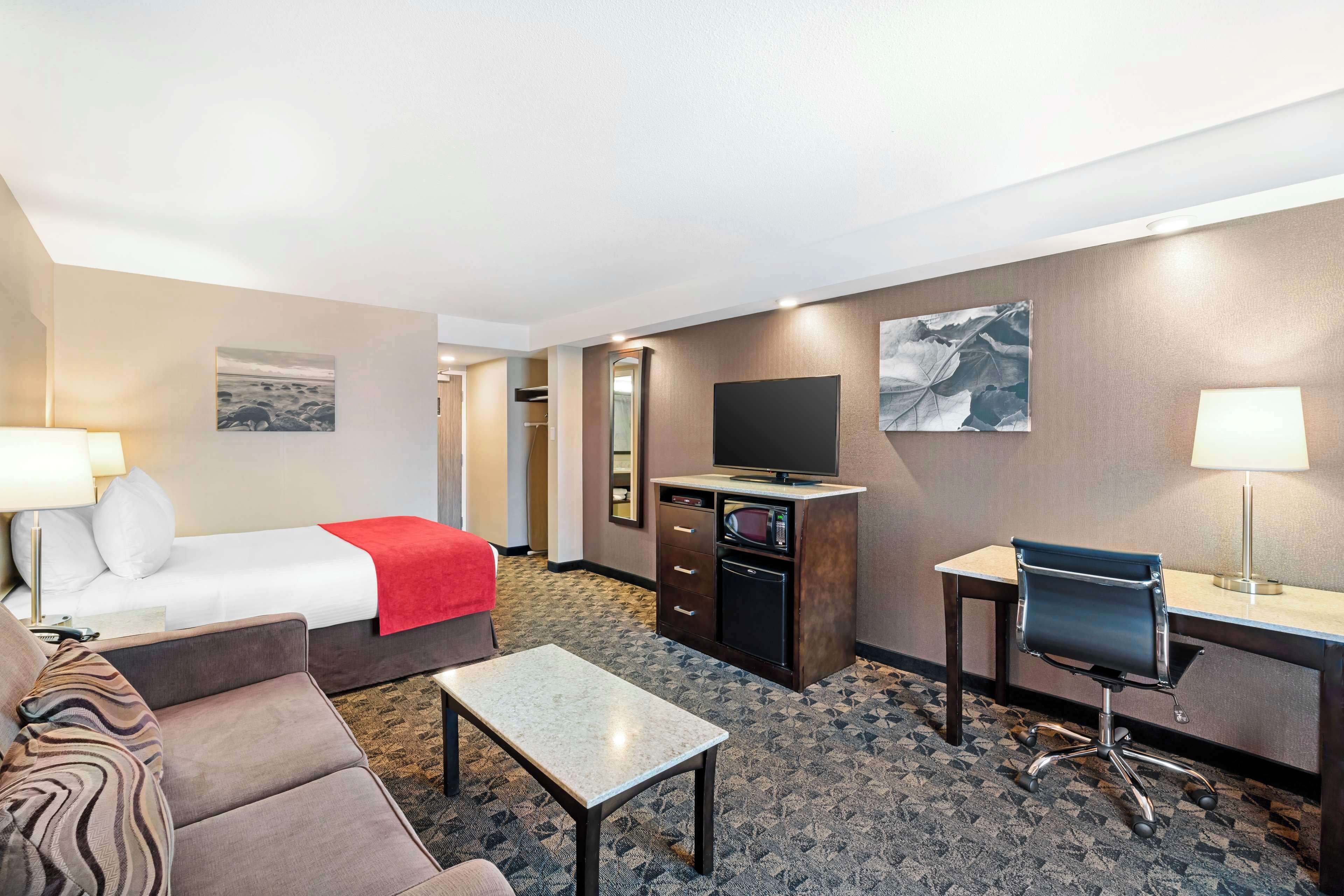 Una habitación de hotel con cama, escritorio, silla, televisor y microondas.