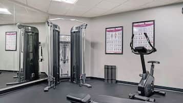 A gym with exercise equipment, a bench, and instructional posters on the wall.